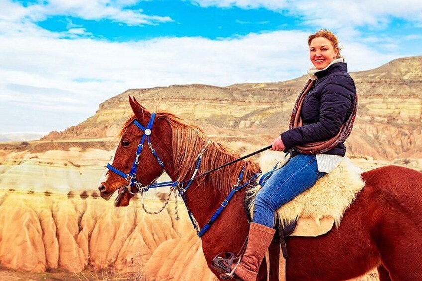 A person riding a horse in a desert landscape with mountains in the background. 4