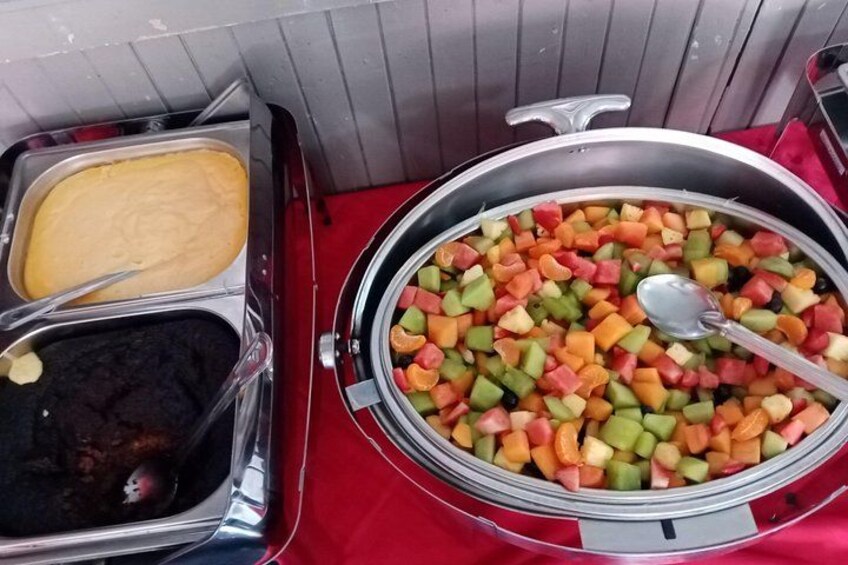 A buffet with various food items, including a large container of diced vegetables and a tray of hummus. 2