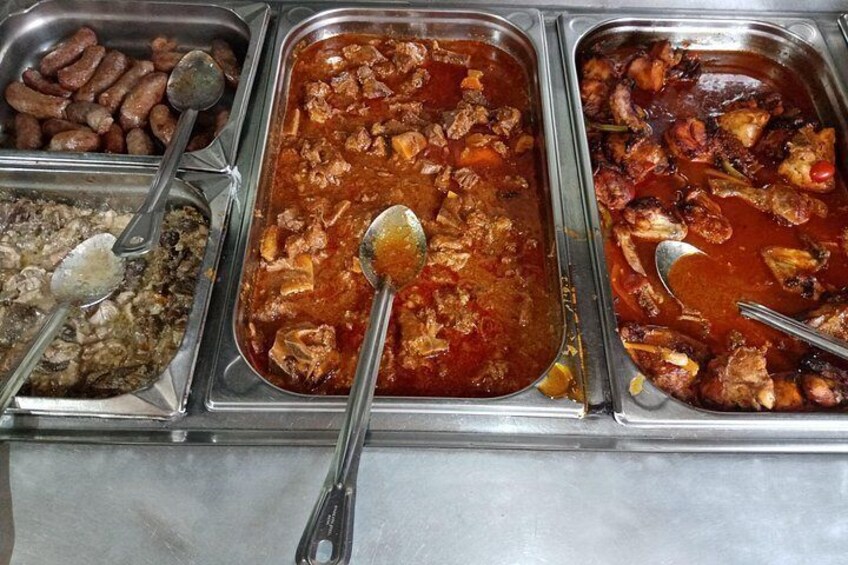 A buffet with various dishes including beans, a meat stew, and a rice dish. 3
