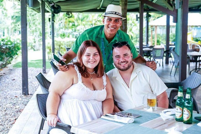 Tres personas sentadas en una mesa al aire libre con bebidas y una carta. 4