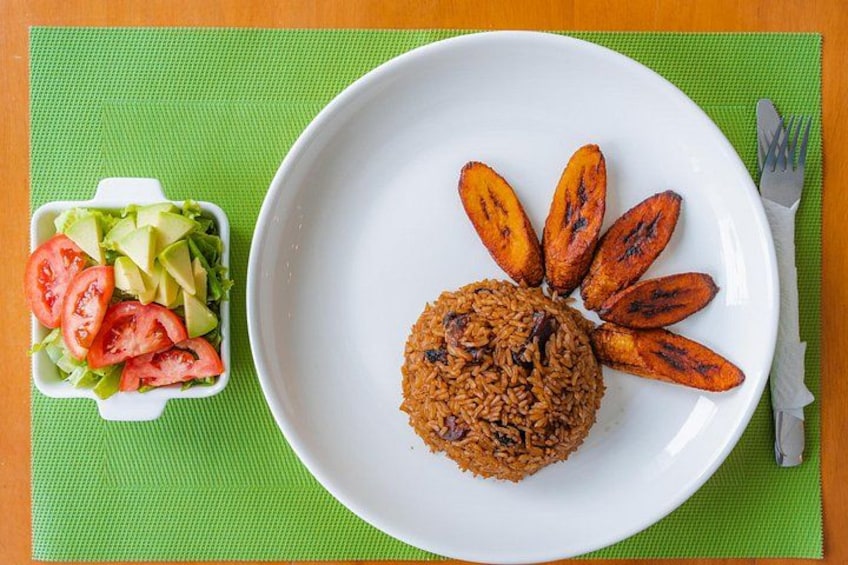 Un plato de arroz con plátanos fritos y una ensalada de tomate y aguacate. 3