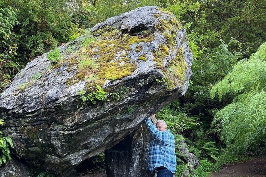 A person climbing a large rock with moss. 5