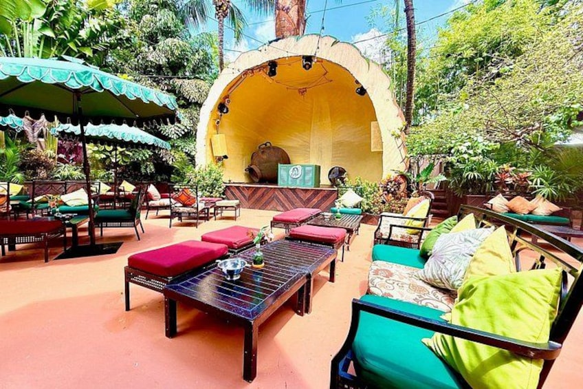 Un espace extérieur aménagé avec des tables, des chaises et des parasols, entouré d’une végétation luxuriante. 4