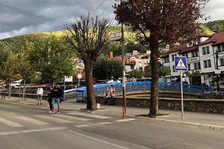 A pedestrian crossing, a blue bridge, and buildings with a hotel sign. 1