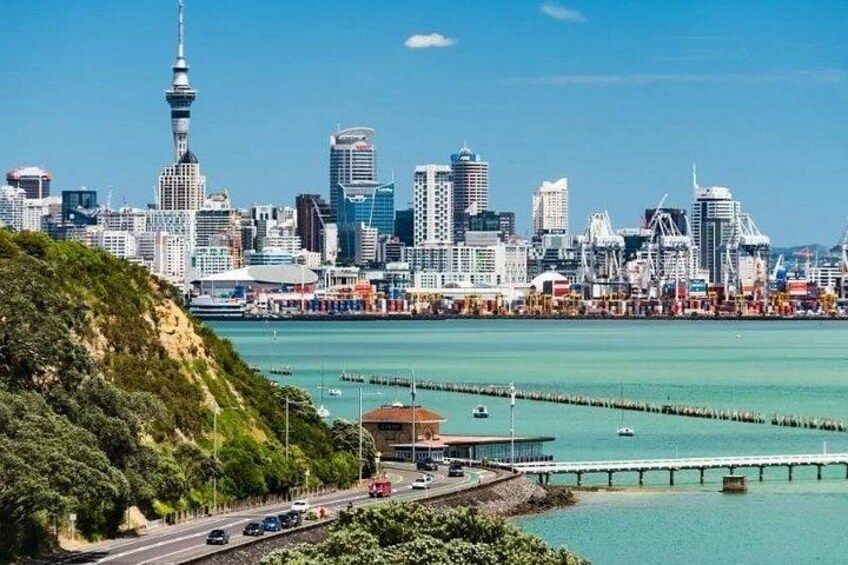 A city skyline with a prominent tower, a waterfront with a pier, and a hilly landscape. 1