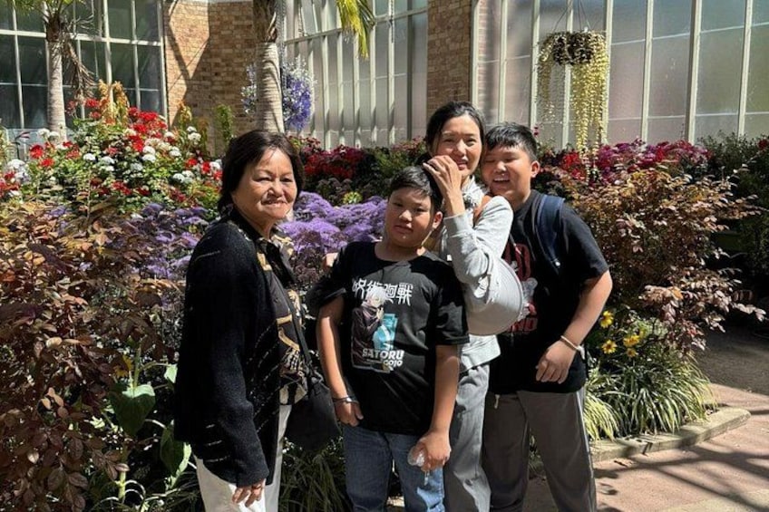 A group of people standing in a garden with various plants and flowers. 4