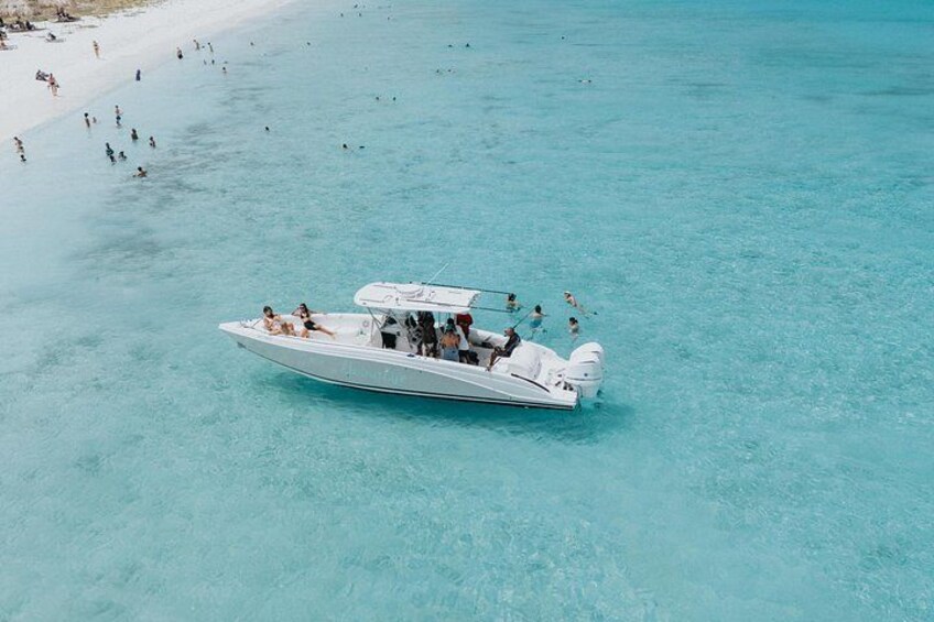 A white boat with people on a turquoise beach. 5
