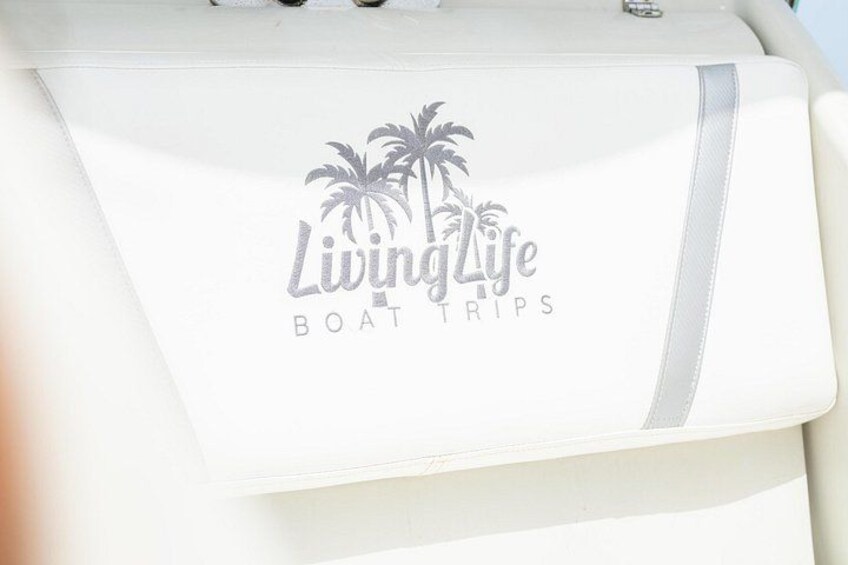 A boat with a logo that reads 'Living Life Boat Trips' and palm tree silhouettes. 2