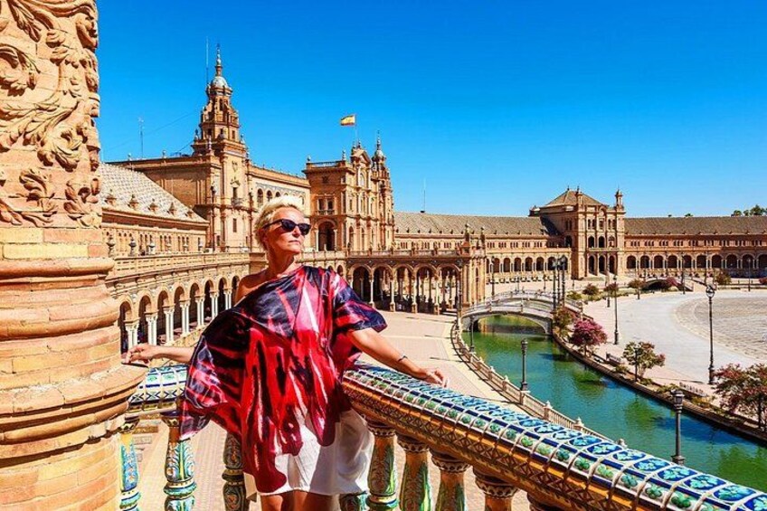 A person standing on a balcony overlooking a historic building with arches and a river. 4