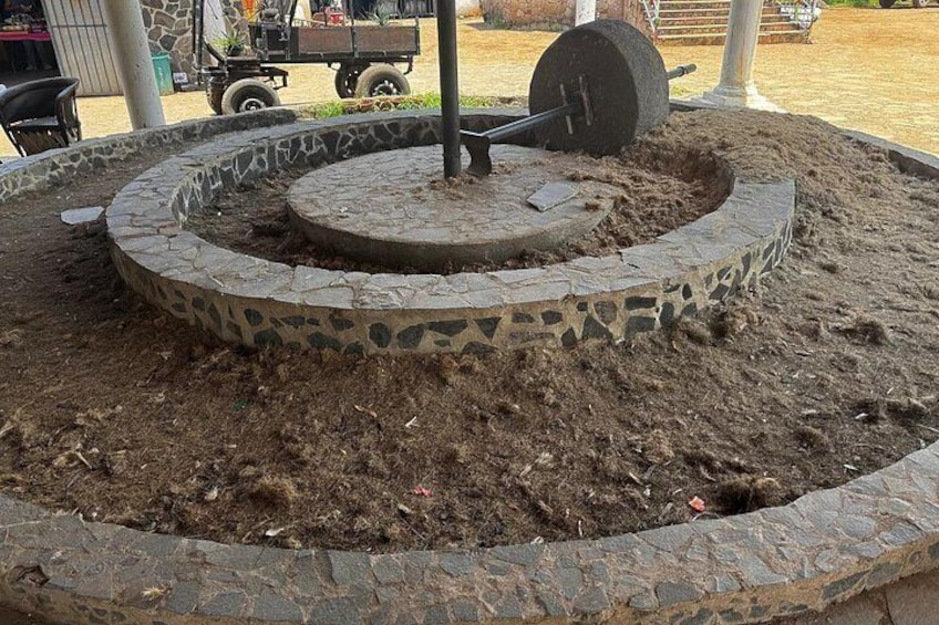A circular stone structure with a central pole and a wheel. 3
