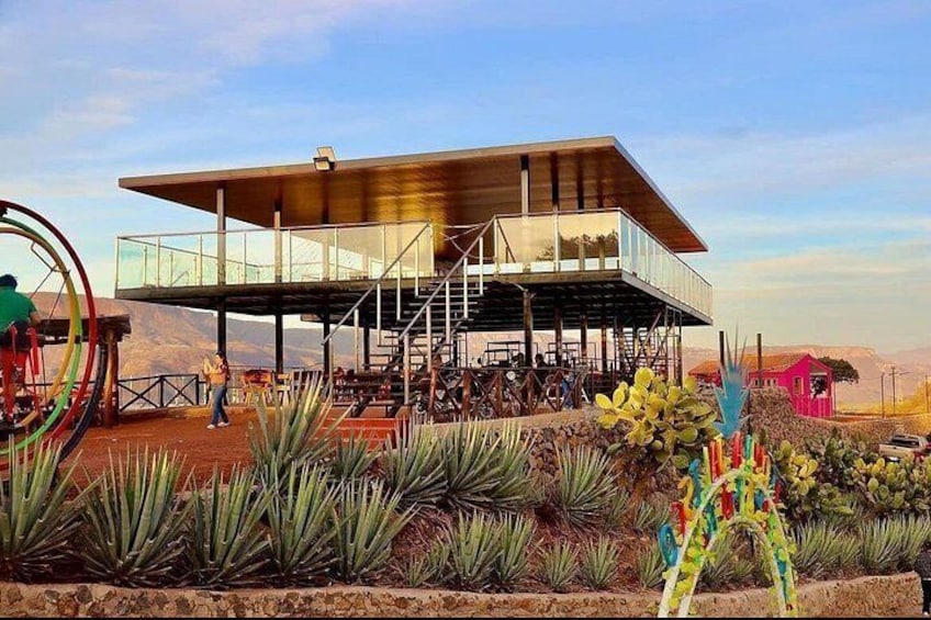 A modern building with a glass facade, surrounded by desert plants and a colorful sculpture. 2