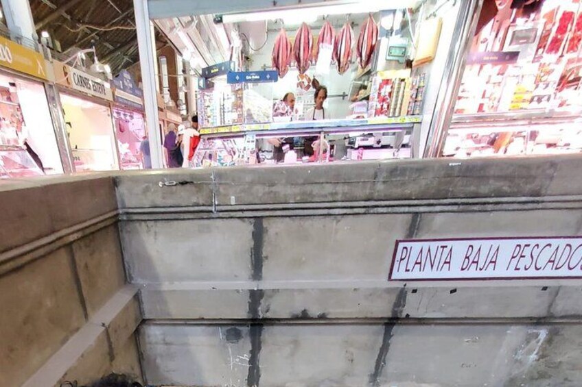 Una bancarella di mercato con un cartello che riporta 'PLANTA BAJA PESCADO' e diversi prodotti a base di carne esposti. 3
