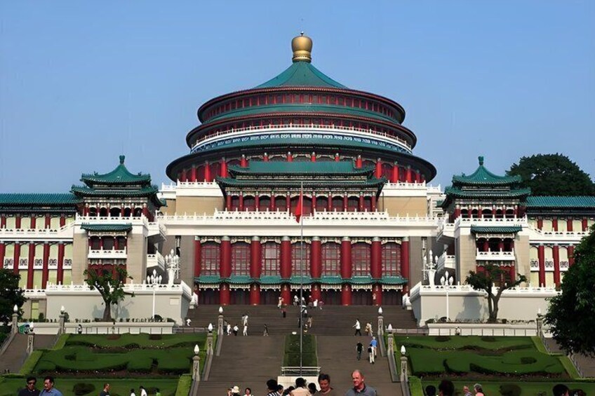 A large traditional building with a green roof and red walls, surrounded by well-maintained gardens and a clear sky. 4