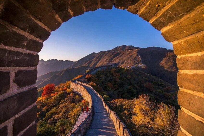 A section of the Great Wall of China with a stone pathway, surrounded by autumn foliage and mountainous terrain. 1