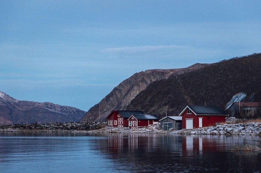 A calm lake with red buildings and mountains in the background. 2
