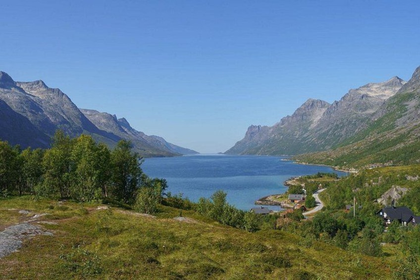 A mountainous landscape with a lake, greenery, and a small settlement. 1