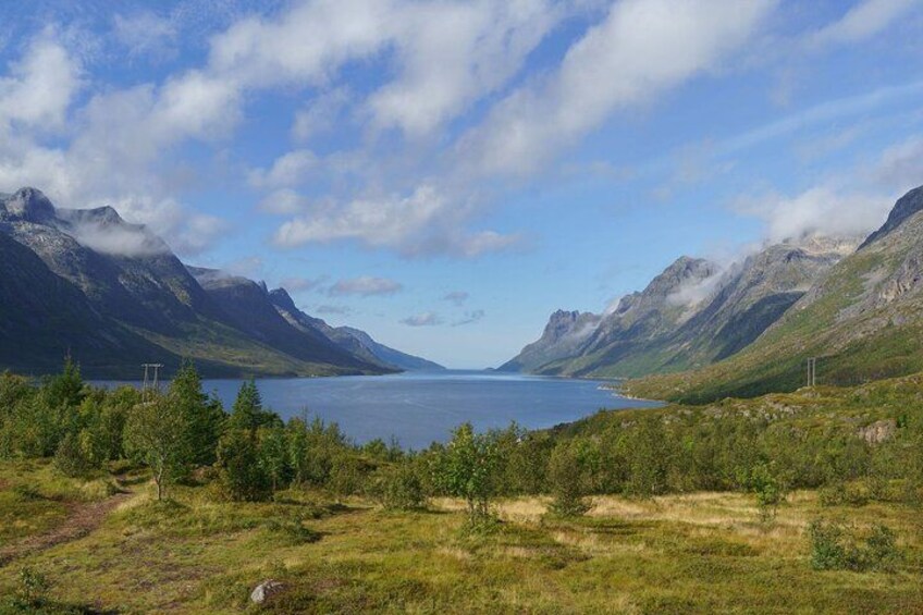 A lake surrounded by mountains, with a clear sky and some clouds. 2