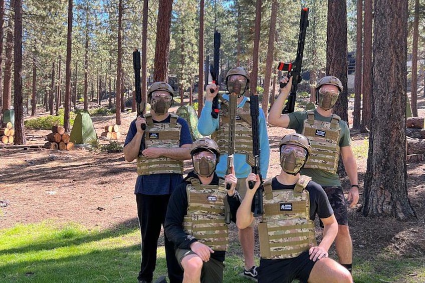 Un grupo de personas con equipo táctico y rifles en un área boscosa. 2