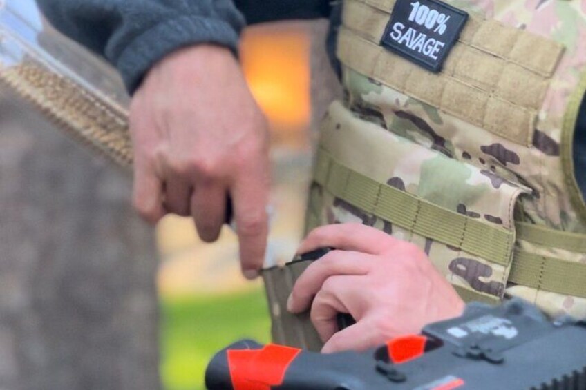 A person in military attire with a camouflage vest and a patch labeled '100% SAVAGE.' 2