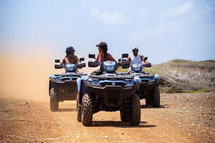 Three people riding ATVs on a dirt path. 1