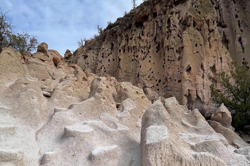 A rocky landscape with large boulders and a cliff with numerous holes. 4