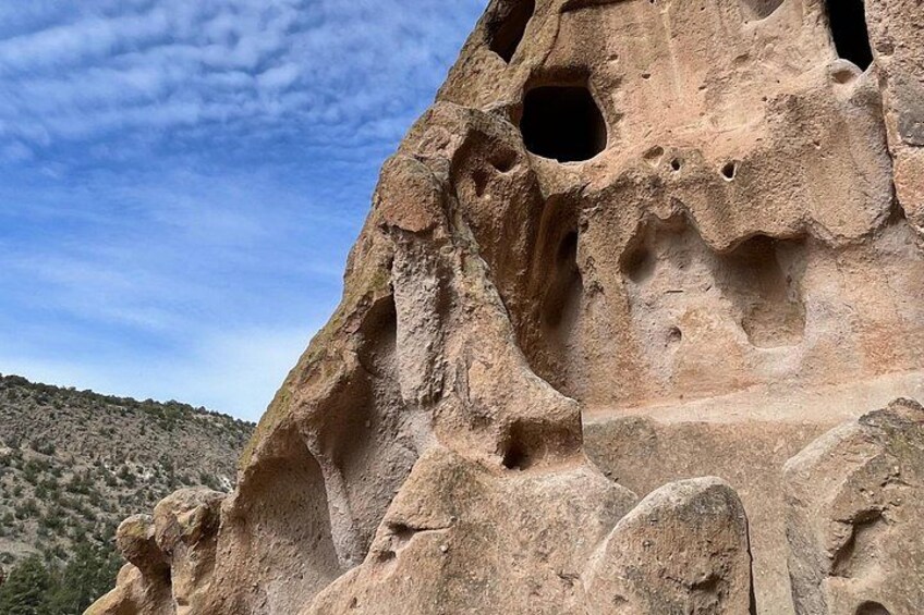 A large rock formation with multiple holes and a clear sky. 3