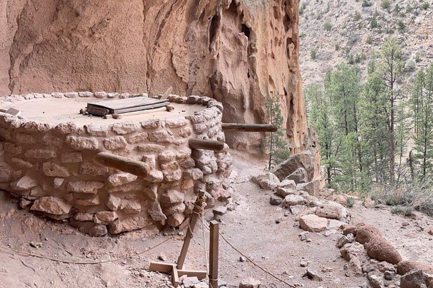 A stone structure with a flat top, surrounded by a rocky cliff and sparse vegetation. 5