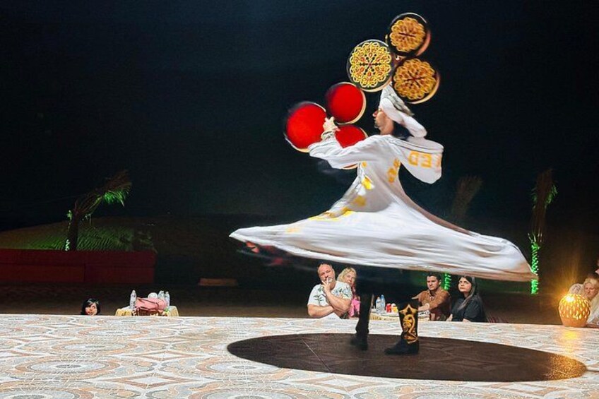A person performing a dance with red and yellow props on a patterned floor. 1