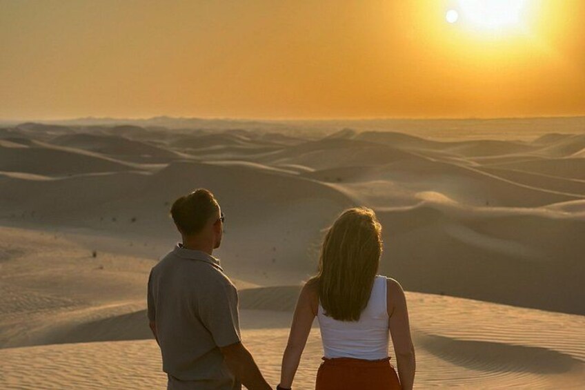 Two people standing on sand dunes during sunset. 2