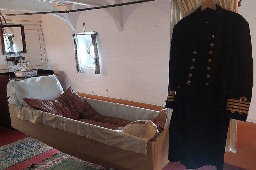 Ein Zimmer mit einem Bett, einer Person in Uniform und einem Spiegel an der Wand. 5