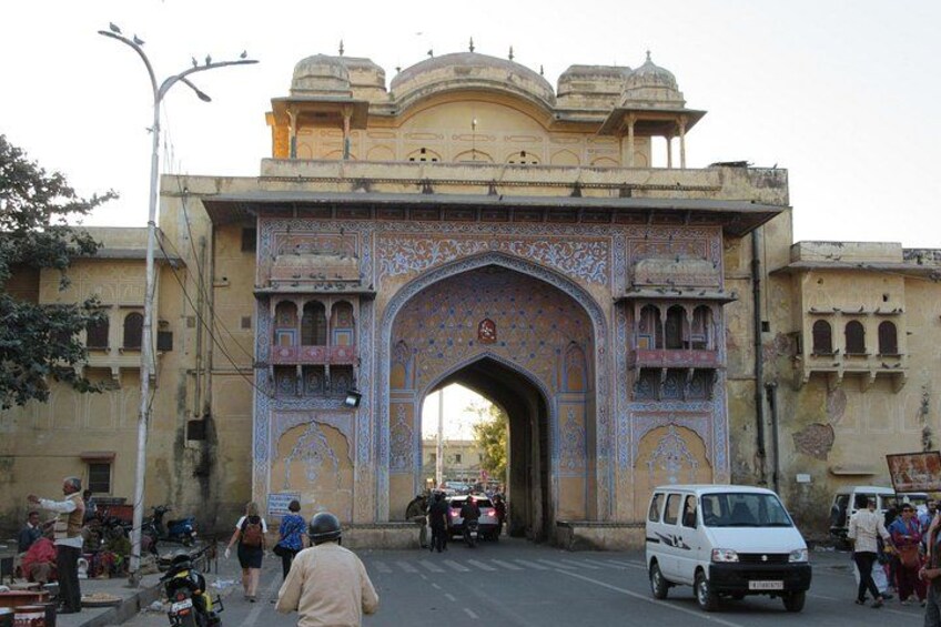 An ornate archway with intricate designs, a street with vehicles and pedestrians, and buildings with traditional architecture. 5
