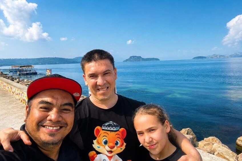 Three people standing by a waterfront with a pier in the background. 2