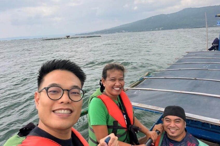 Three people on a boat with a mountainous landscape in the background. 4