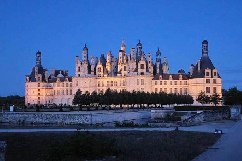 A large, historic building with multiple towers and a well-maintained garden in front. 4