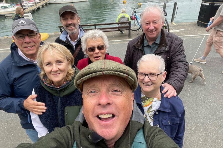A group of people standing by a waterfront with boats in the background. 4