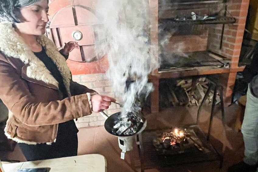 Una persona cucina all'aperto usando un tradizionale focolare, con fumo visibile. 5