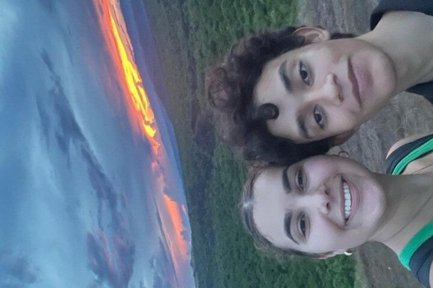 Two people standing near a body of water with a sunset. 2