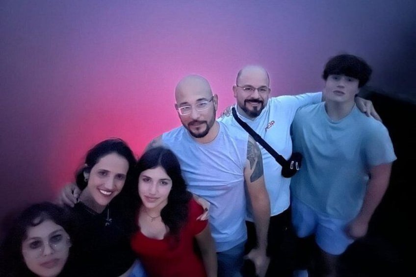 A group of people posing together in a dimly lit room with a purple hue. 3