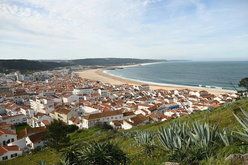 A coastal town with red-roofed buildings, a beach, and a clear sky. 3
