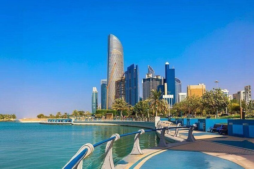 A waterfront cityscape with modern skyscrapers, a clear blue sky, and a calm sea. 2