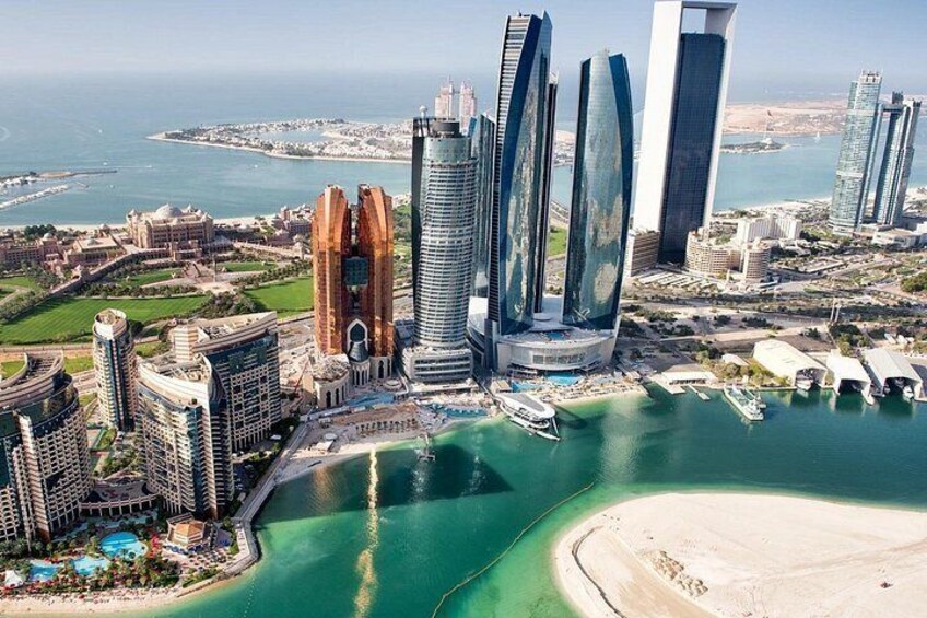 A coastal cityscape with modern skyscrapers, a marina, and a beach. 4