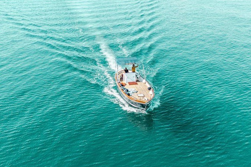 Un bote en aguas turquesas con estelas de olas. 4