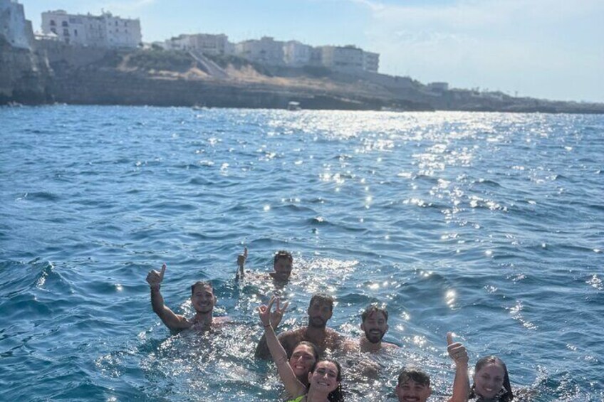 Un groupe de personnes nage dans une étendue d’eau, avec des bâtiments en arrière-plan. 3