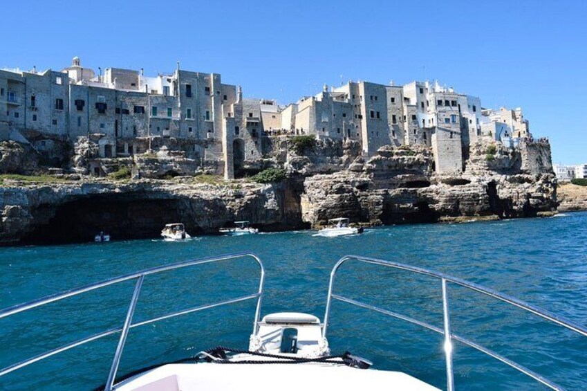 A boat with a rocky coastline and white buildings in the background. 5