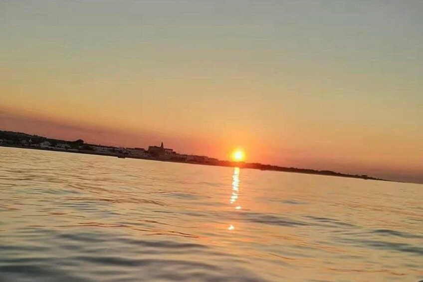 A sunset over a calm body of water with a distant shoreline. 4