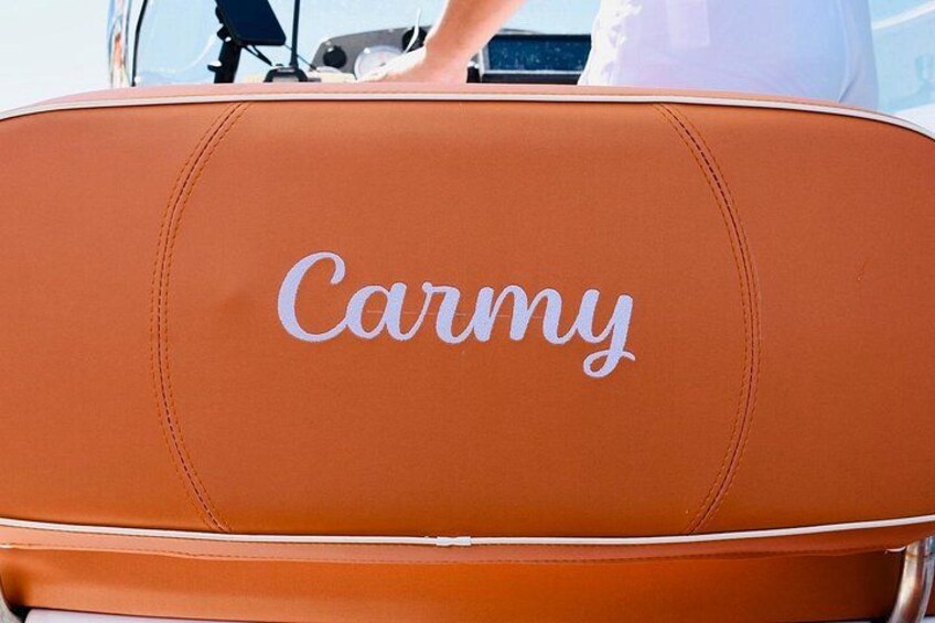 A brown leather seat with the word 'Carmy' embroidered on it. 3