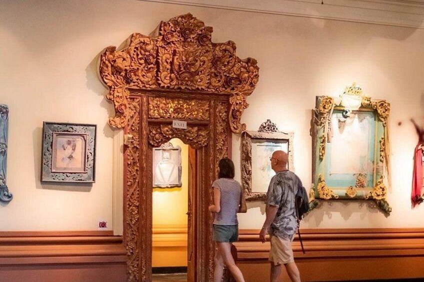 An ornate wooden door with intricate carvings, a framed picture on the wall, and a mirror with a decorative frame. 2