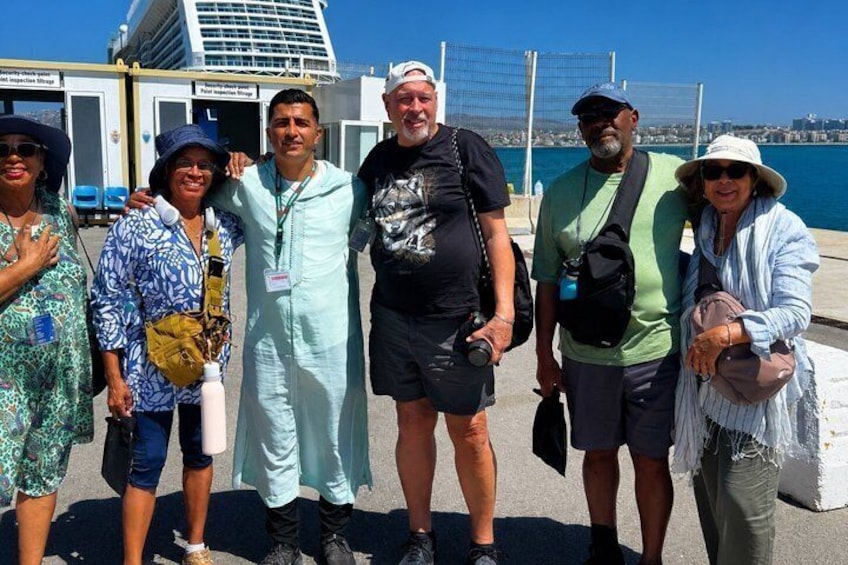 A group of people standing on a dock with a ship in the background. 2