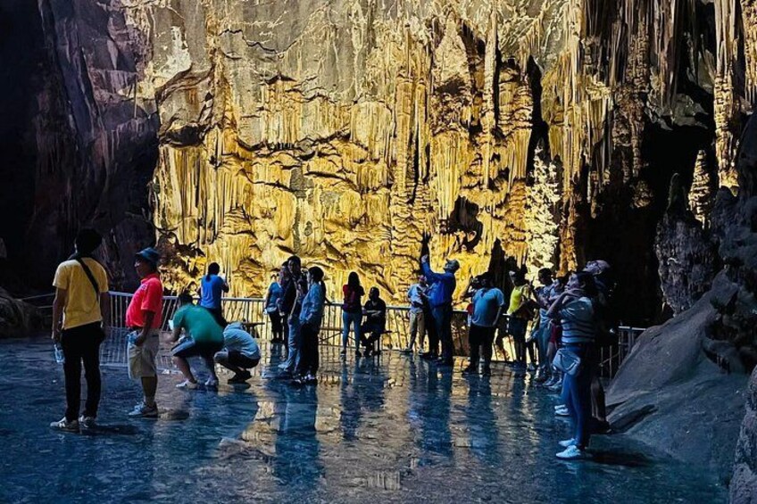 A group of people exploring a cave with stalactites. 1