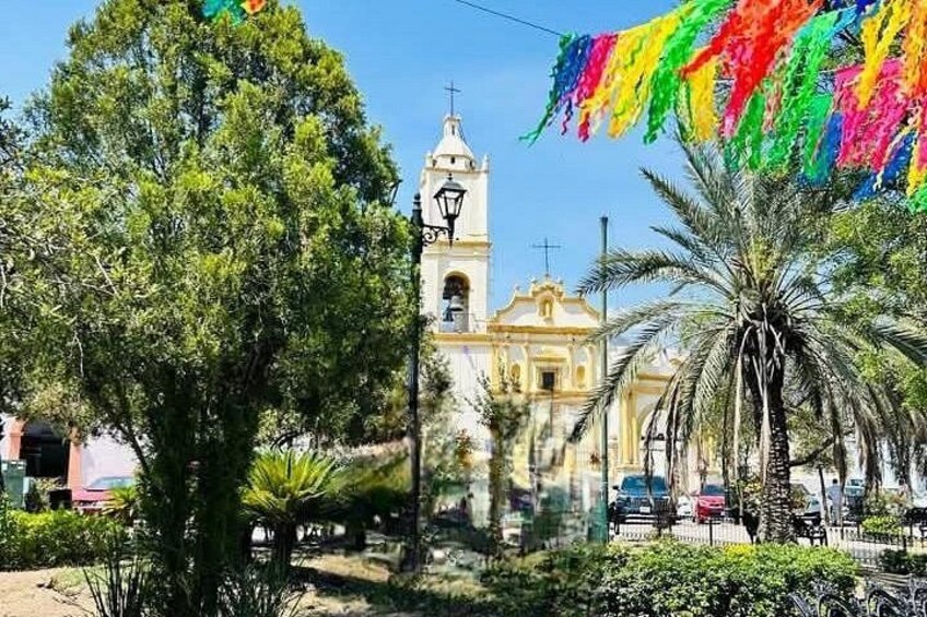 A church with a bell tower, palm trees, and a colorful flag. 4